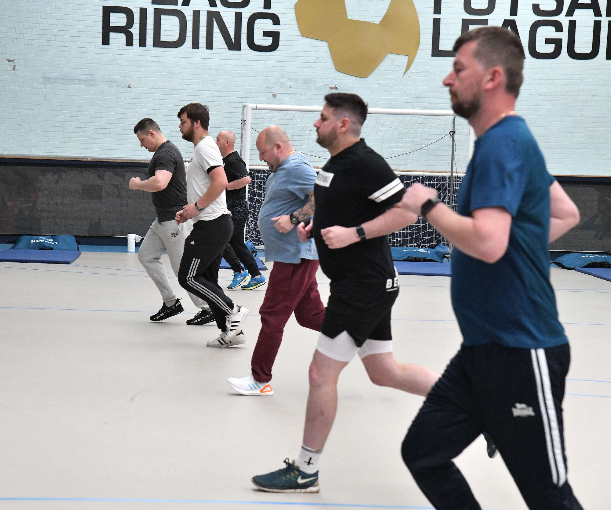 A line of men running in a sports hall